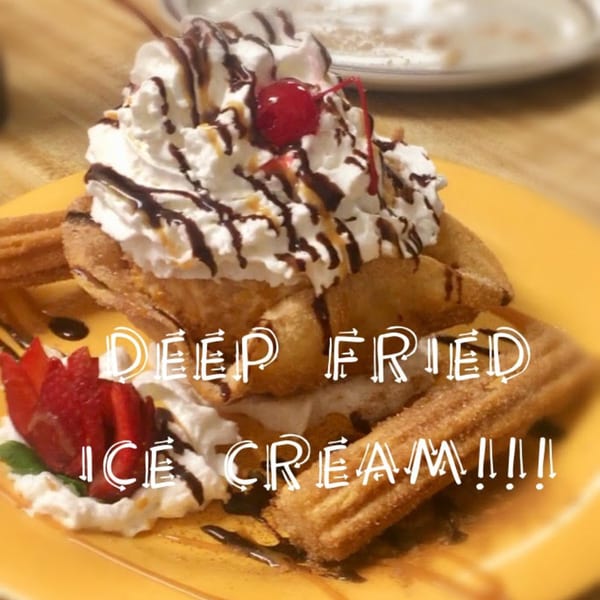 Deep-fried ice cream with whipped cream, chocolate drizzle, a cherry, strawberries, and churros.