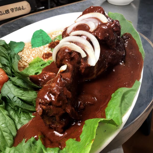 Money Pancho's Mexican mole dish with chicken, onions, and lettuce on a white plate.