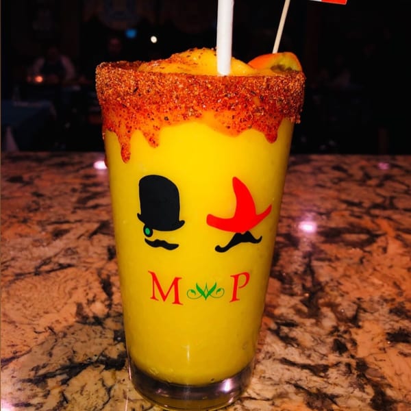 A Money Pancho Mexican Restaurant mango drink with a chili-lime rim and a decorative straw.